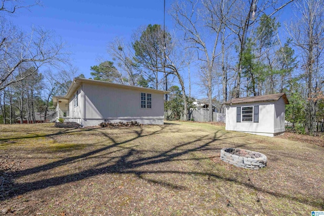 exterior space featuring an outbuilding, a yard, fence, and an outdoor fire pit