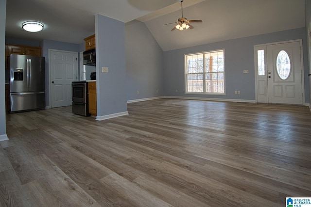 unfurnished living room with vaulted ceiling, a ceiling fan, baseboards, and wood finished floors