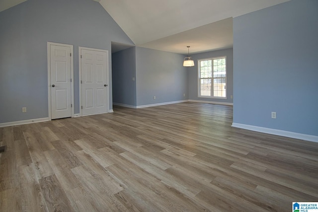 empty room featuring vaulted ceiling, baseboards, and wood finished floors