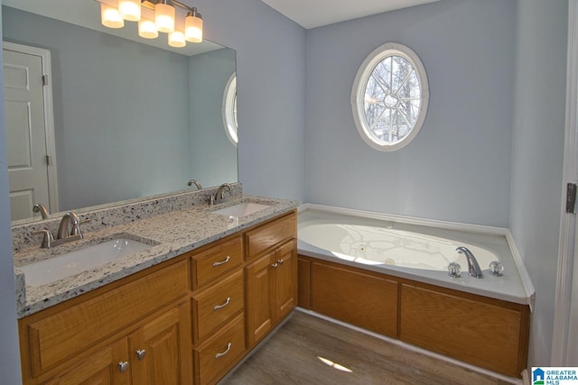 bathroom with a garden tub, wood finished floors, double vanity, and a sink