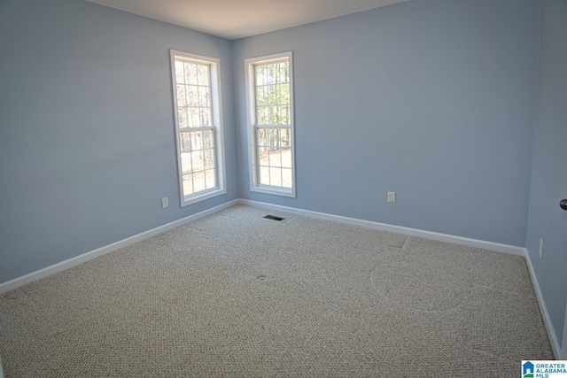 carpeted spare room with visible vents and baseboards