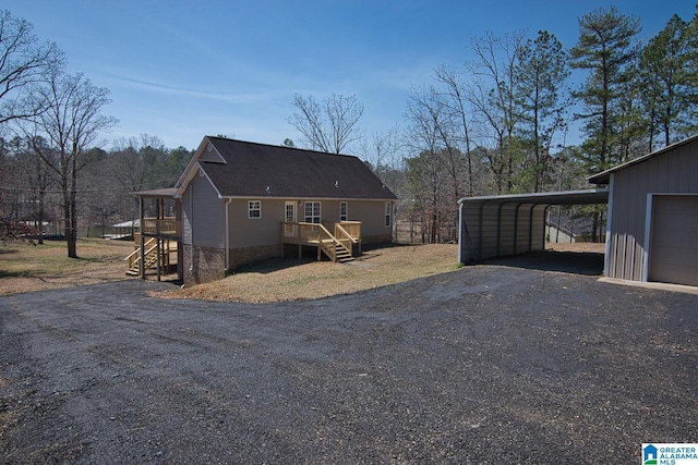 back of house featuring stairs, aphalt driveway, and roof with shingles