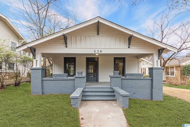 bungalow-style house with a porch, board and batten siding, and a front yard