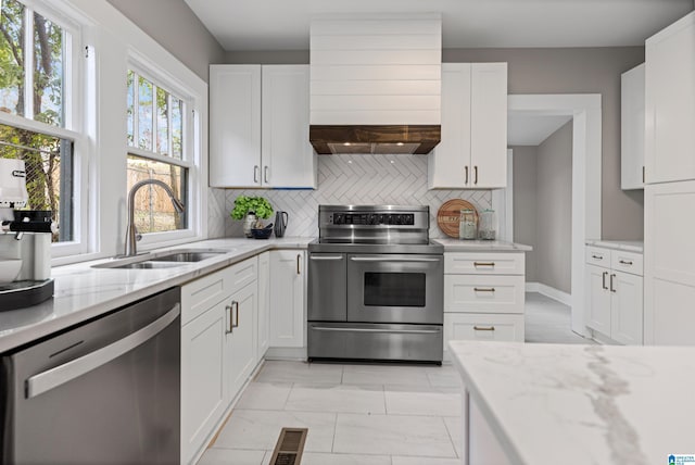 kitchen with visible vents, a sink, ventilation hood, appliances with stainless steel finishes, and decorative backsplash