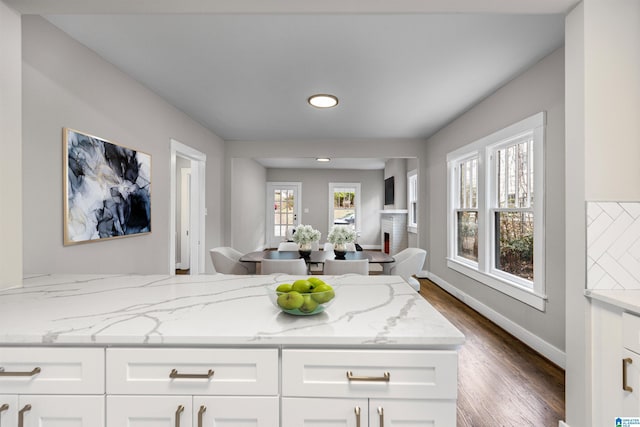 bathroom featuring wood finished floors, baseboards, and a lit fireplace