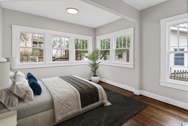 bedroom with dark wood finished floors, multiple windows, and baseboards