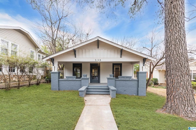 bungalow with board and batten siding, brick siding, a porch, and a front lawn