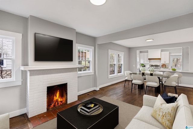 living area featuring visible vents, baseboards, dark wood-style floors, and a fireplace