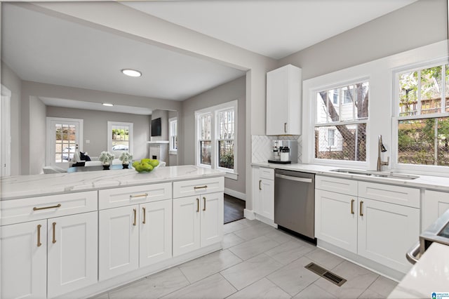 kitchen with visible vents, a sink, stainless steel dishwasher, white cabinets, and light stone countertops