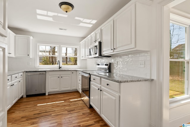 kitchen with white cabinets, visible vents, appliances with stainless steel finishes, and a sink