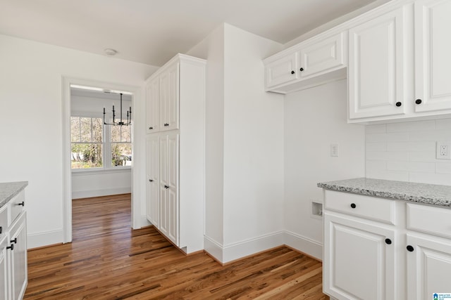 kitchen featuring light stone counters, backsplash, baseboards, and light wood-style floors