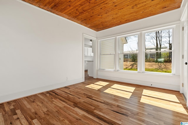 unfurnished room featuring wood finished floors, wood ceiling, and baseboards