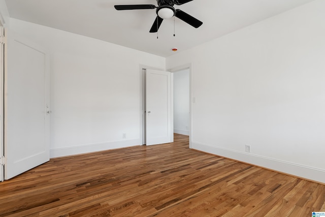 spare room with baseboards, wood finished floors, and a ceiling fan