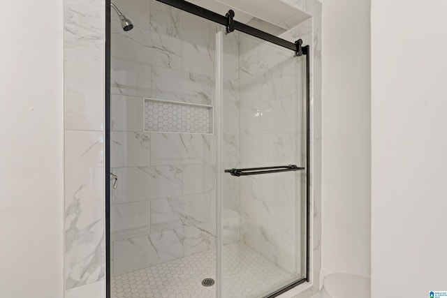 bathroom featuring toilet and a marble finish shower