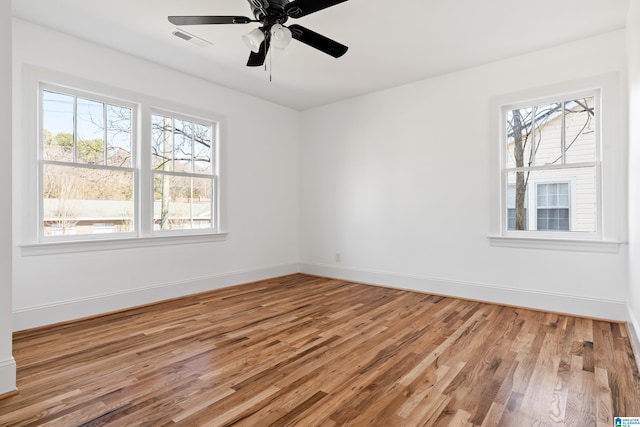 empty room with visible vents, ceiling fan, baseboards, and wood finished floors