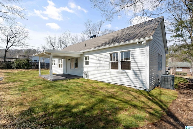 back of property with central air condition unit, metal roof, a yard, and fence