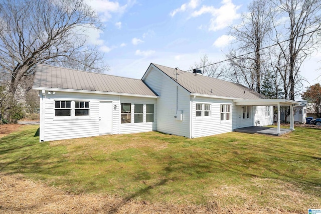 back of house featuring metal roof, a patio, and a lawn