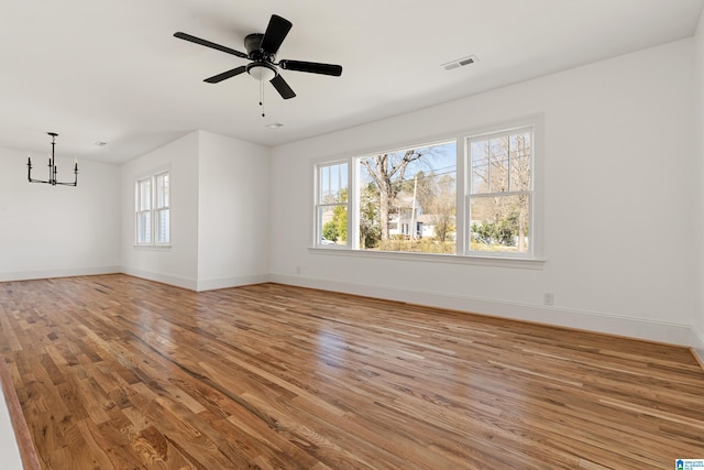 empty room with visible vents, baseboards, a healthy amount of sunlight, and wood finished floors