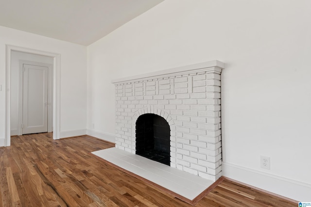 unfurnished living room featuring a fireplace, baseboards, and wood finished floors