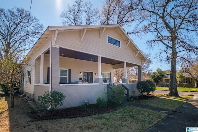 view of property exterior featuring crawl space, covered porch, a lawn, and brick siding