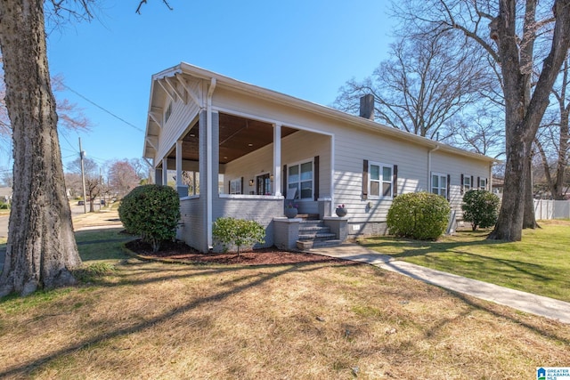 view of front facade with a front yard, brick siding, and a chimney