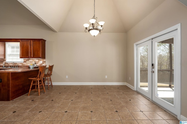 dining room with a notable chandelier, lofted ceiling, french doors, light tile patterned floors, and baseboards