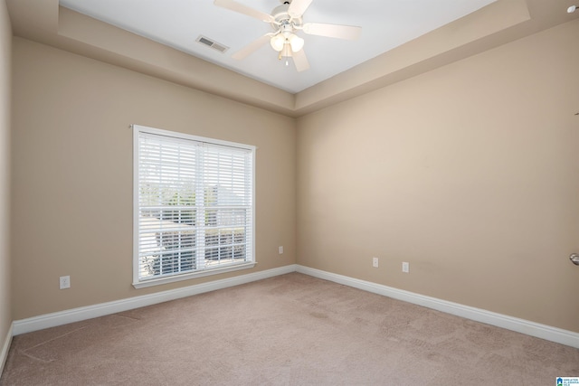 carpeted spare room featuring visible vents, baseboards, and a ceiling fan