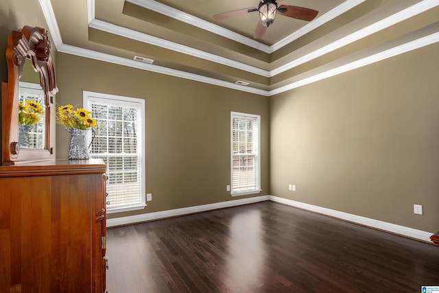 spare room with dark wood-style floors, baseboards, visible vents, ornamental molding, and a raised ceiling