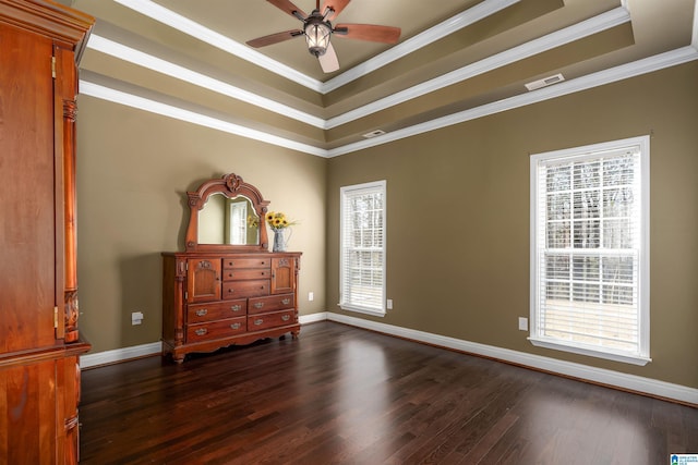 bedroom with a tray ceiling, dark wood-type flooring, visible vents, and ornamental molding