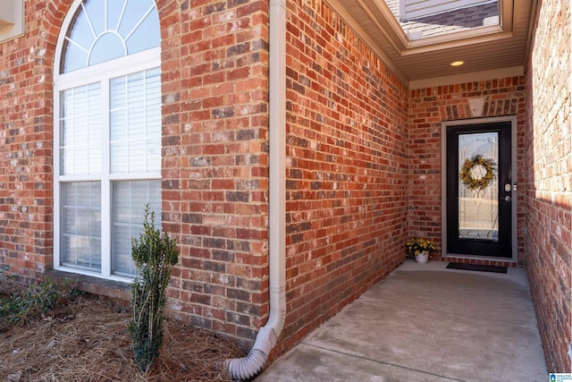 doorway to property with brick siding and roof with shingles