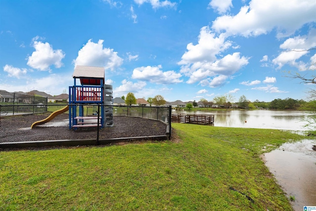 communal playground featuring a yard, a water view, and fence