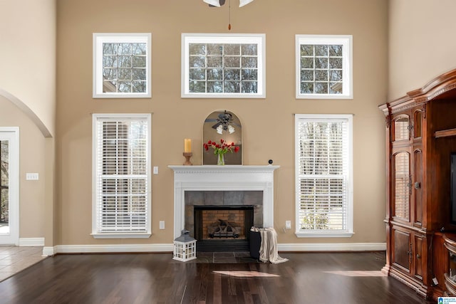 living room with a fireplace with flush hearth, a high ceiling, and wood finished floors