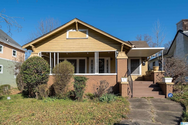 bungalow-style home featuring covered porch and brick siding