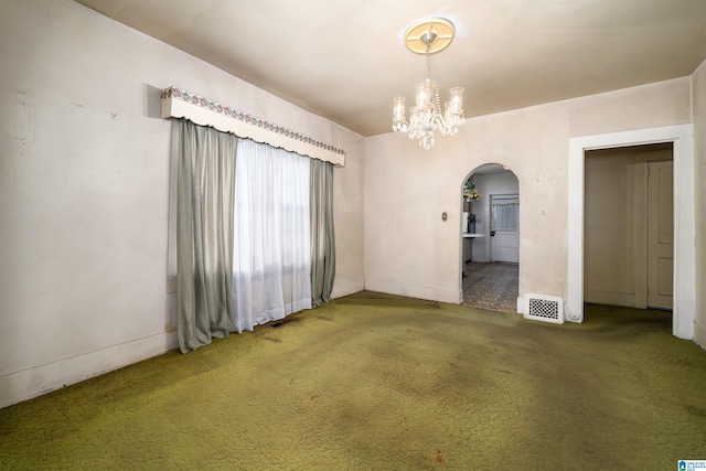 carpeted spare room featuring an inviting chandelier, arched walkways, and visible vents