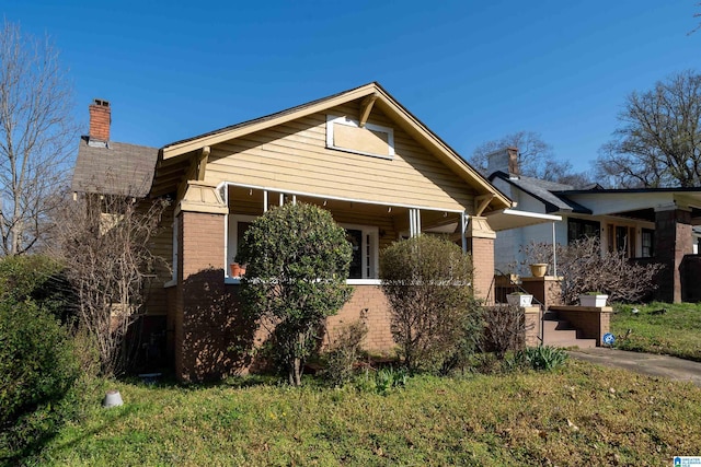 bungalow-style home featuring brick siding and a chimney