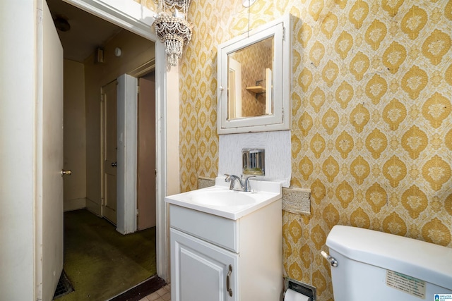 bathroom with wallpapered walls, toilet, and vanity