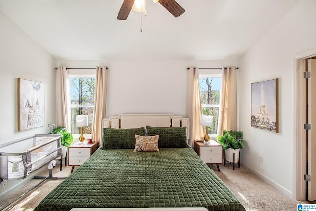 bedroom featuring multiple windows, light colored carpet, baseboards, and vaulted ceiling