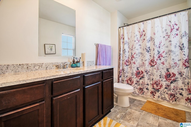 full bathroom with curtained shower, toilet, vanity, and stone finish floor