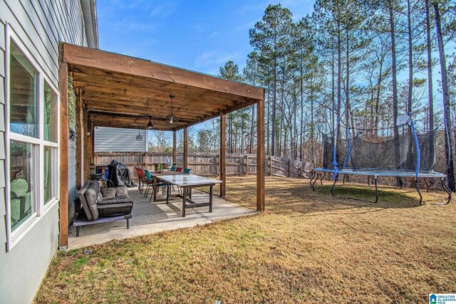 view of yard featuring a patio area, a fenced backyard, ceiling fan, and a trampoline