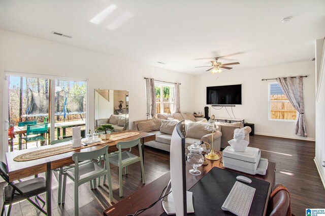 living room with dark wood finished floors, baseboards, visible vents, and ceiling fan