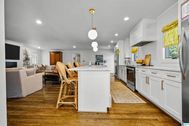 kitchen with premium range hood, light stone counters, white cabinetry, appliances with stainless steel finishes, and dark wood-style flooring