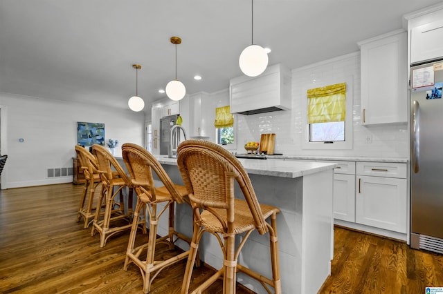 kitchen with premium range hood, dark wood-style flooring, white cabinetry, stainless steel fridge, and backsplash