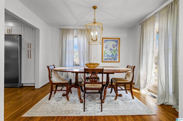 dining room with a notable chandelier, wood finished floors, and baseboards