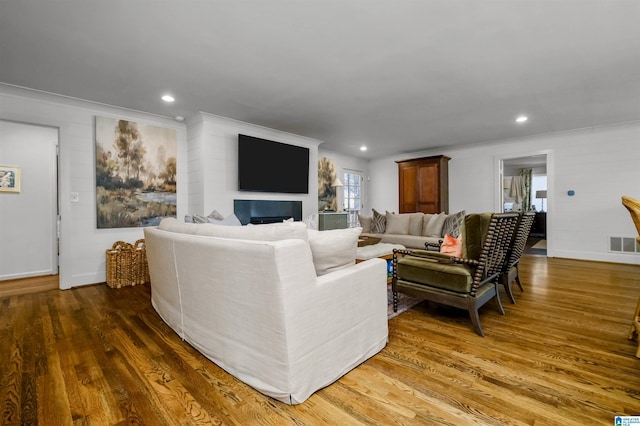 living area featuring recessed lighting, visible vents, wood finished floors, and ornamental molding