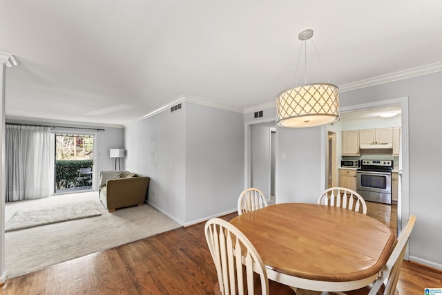 dining area with visible vents, wood finished floors, and crown molding