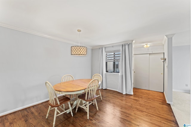 dining room with ornamental molding, baseboards, and wood finished floors