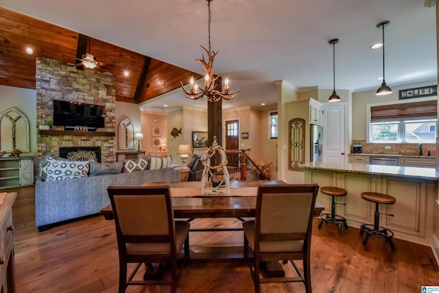 dining area featuring wood finished floors, a fireplace, crown molding, lofted ceiling, and wood ceiling