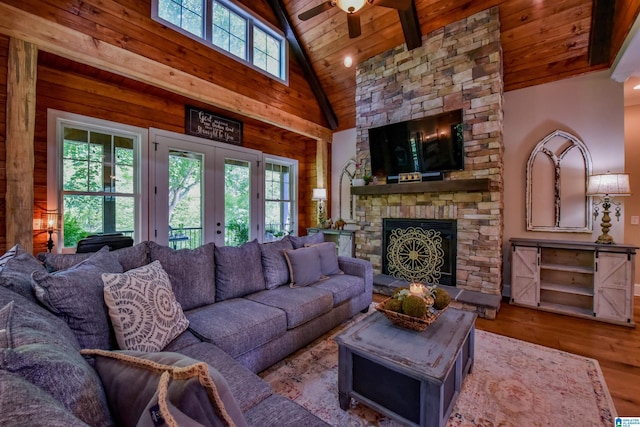 living area featuring wooden walls, wood ceiling, a fireplace, french doors, and wood finished floors