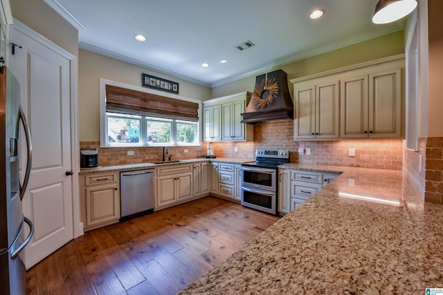 kitchen with premium range hood, cream cabinetry, a sink, stainless steel appliances, and light stone countertops