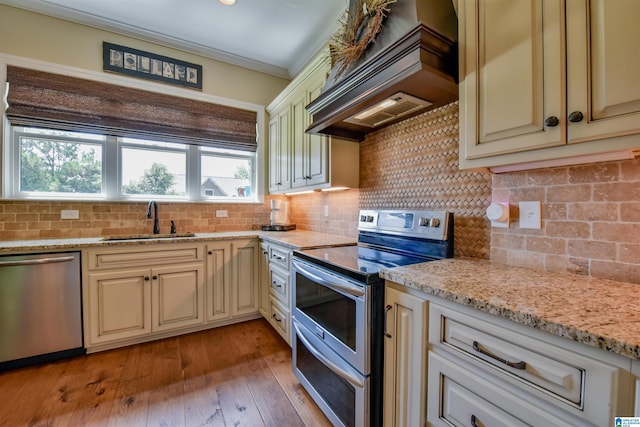 kitchen featuring a sink, cream cabinetry, custom exhaust hood, and appliances with stainless steel finishes